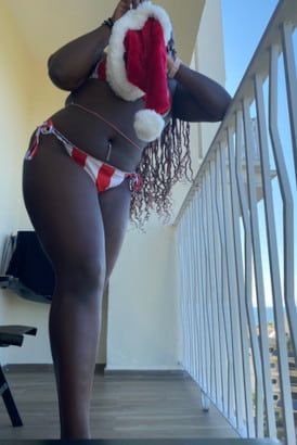 Curvy ebony girl on a landing holding a Christmas hat to hide her face
