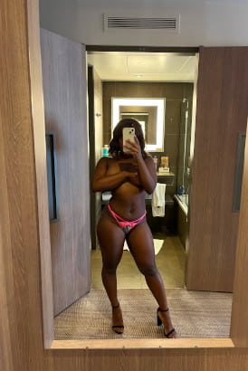 Black girl in pink panties taking a selfie in a hotel room mirror