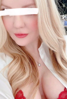 Fair skinned blonde in red bra taking a close up selfie