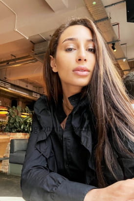 Girl with long brown hair taking a selfie in a cafe