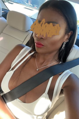 Slender black girl in a white dress sitting in a car