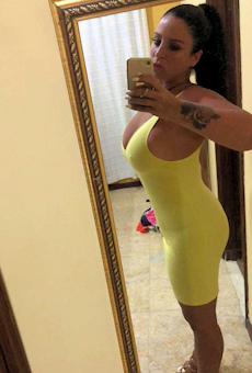 very busty escort i a tight yellow dress taking a selfie in a mirror
