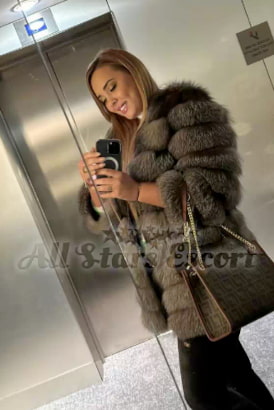 Beautiful girl in a fur coat standing by the door of a lift
