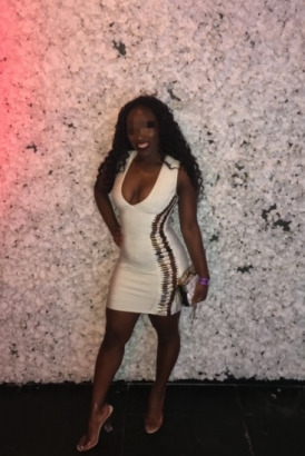 Slim and petite black escort in a white dress and high heels