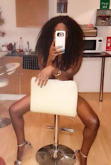 Beautiful black escort taking a selfie whilst sitting on a chair