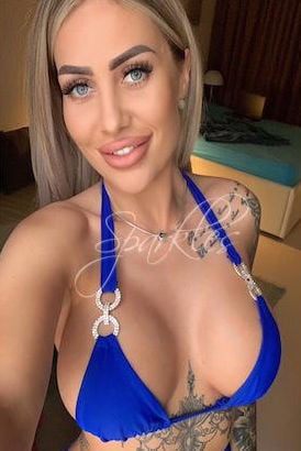 Very busty blonde with tattoos wearing a blue bikini