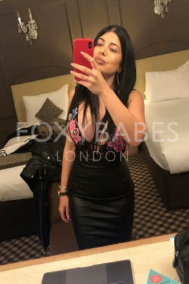 Busty brunette taking a selfie in front of a mirror