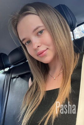 Baby faced young blonde girl sitting in the back seat of a car